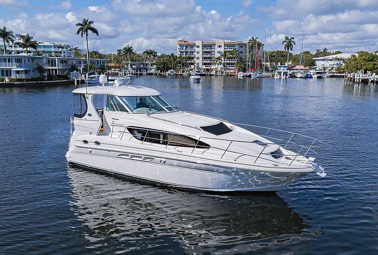 Slide: The Image of 2005 Sea Ray 390 Motor Yacht on calm water, with scenic waterfront background. - 0