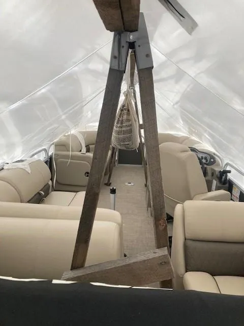 Slide: The Image of 2023 Sun Tracker PB 22 RF boat interior under protective cover, featuring beige seating. - 10