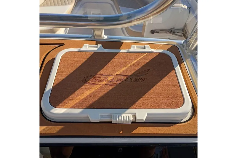 Slide: The Image of 2026 Bulls Bay 255 Center Console boat hatch with logo, featuring sleek design and wood finish. - 18