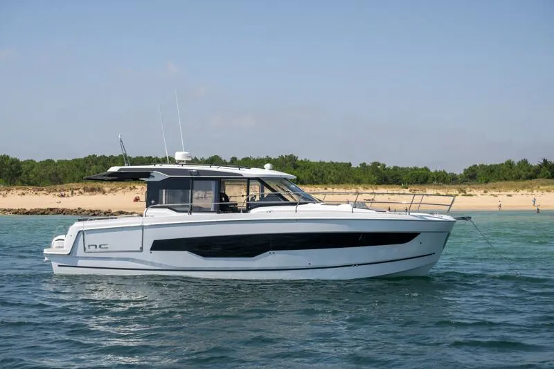 Slide: The Image of 2025 Jeanneau NC 1295 Coupe yacht cruising near a sandy beach. - 5