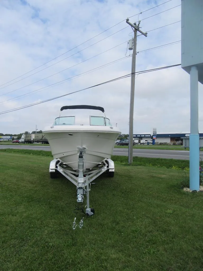 Slide: The Image of 2025 Robalo R207 Dual Console boat on trailer, parked on grass near road. - 1