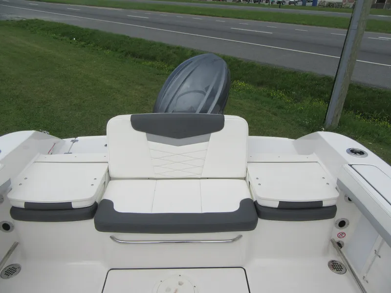 Slide: The Image of 2025 Robalo R207 Dual Console boat, rear seating area with outboard motor, parked on grass. - 14