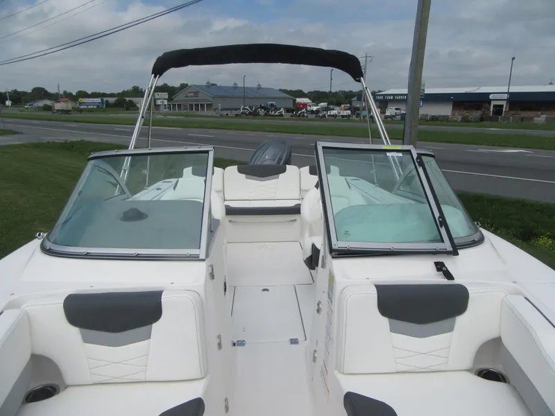 Slide: The Image of 2025 Robalo R207 Dual Console boat with open seating and windshield, parked near a road. - 5
