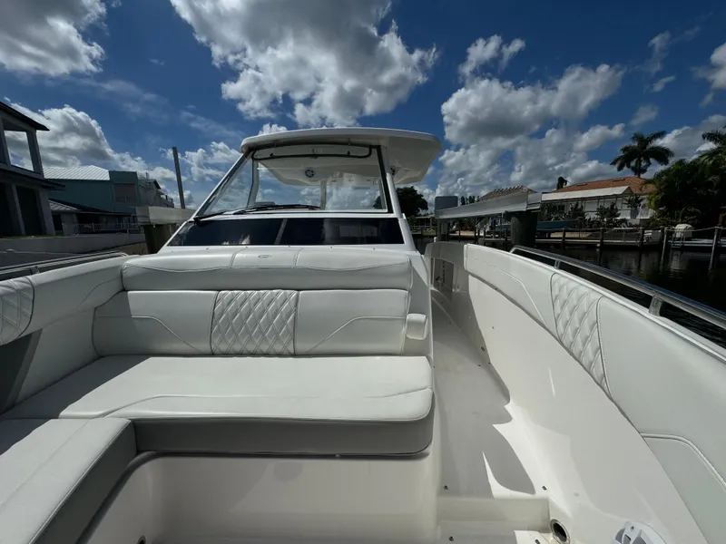 Slide: The Image of 2022 Regal 33 SAV boat with white seating, docked under a partly cloudy sky. - 20