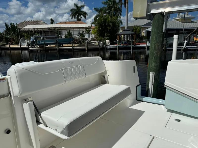 Slide: The Image of 2022 Regal 33 SAV boat interior with white seating, docked near waterfront homes. - 7