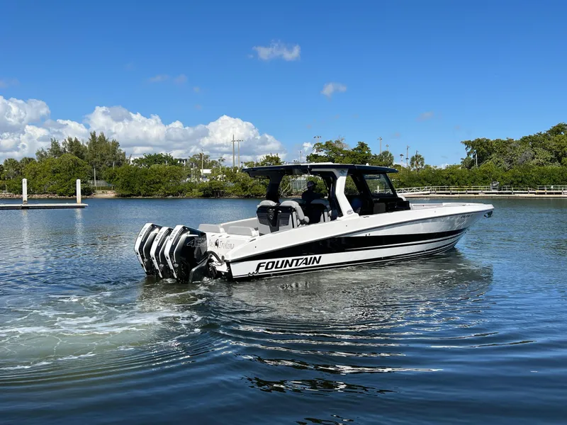 Slide: The Image of 2023 Fountain 38 SCX boat cruising on a calm lake under a clear blue sky. - 2