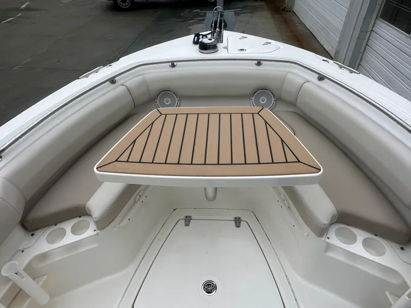 Slide: The Image of 2022 Boston Whaler 230 Outrage boat interior with cushioned seating and wooden table. - 4