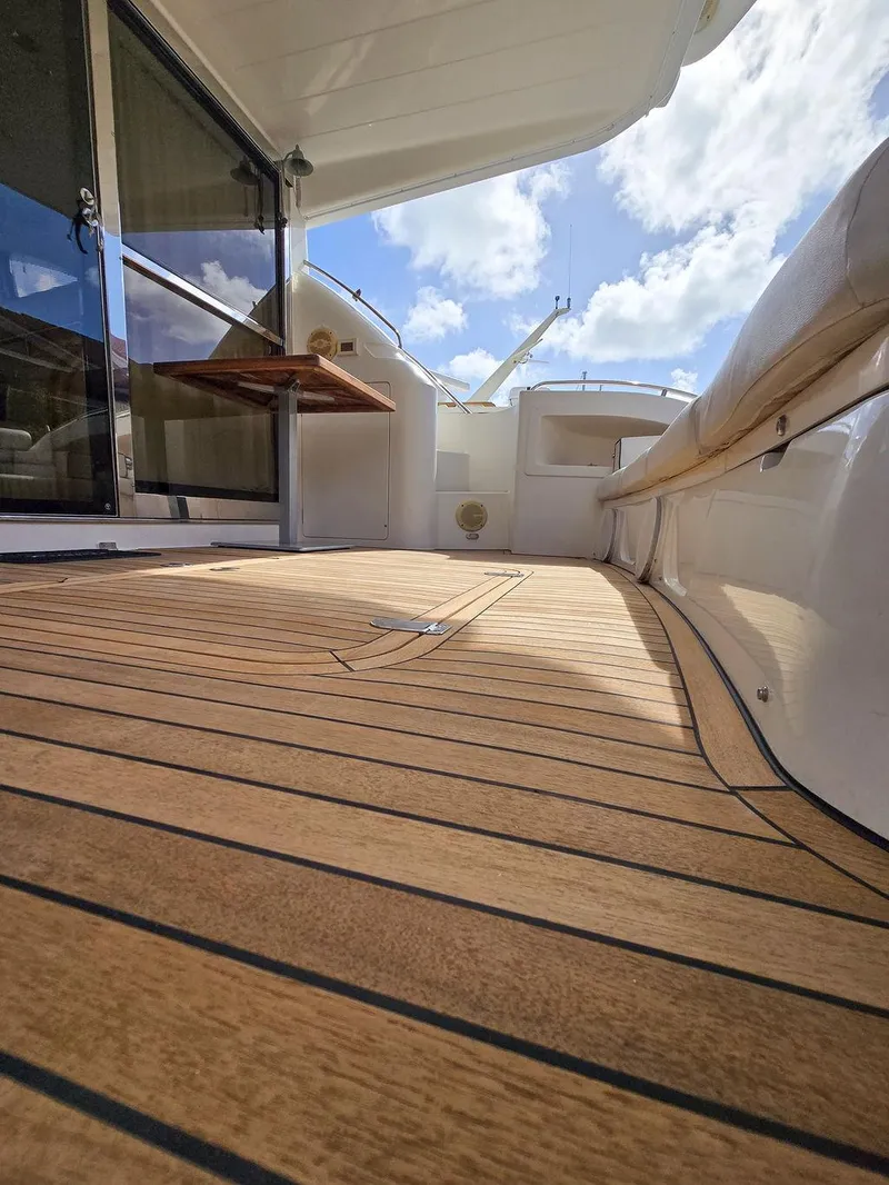 Slide: The Image of 1998 Viking Princess 56 Sport Cruiser deck with wooden flooring and clear sky view. - 13