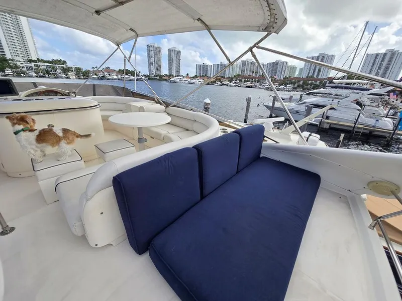 Slide: The Image of 1998 Viking Princess 56 Sport Cruiser yacht with blue seating, docked in a marina. - 49
