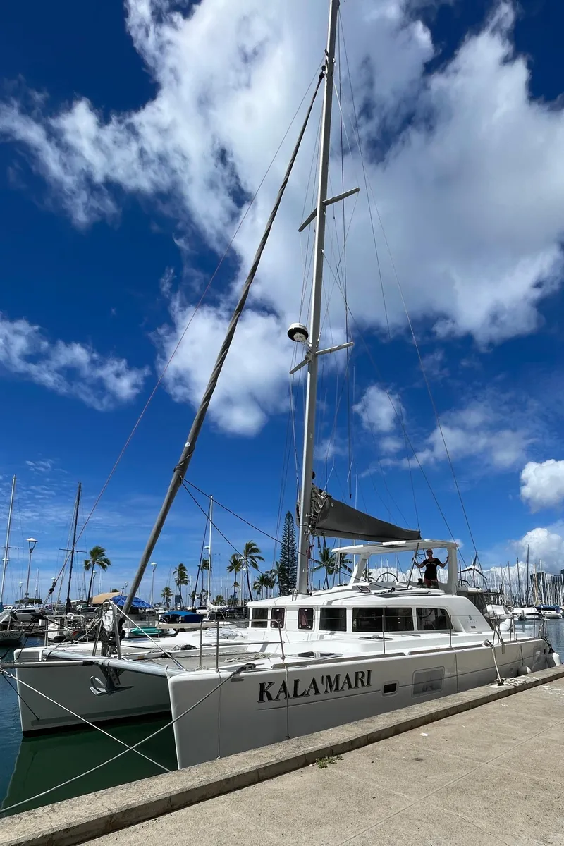 Slide: The Image of Lagoon 440 catamaran docked at marina under blue sky, 2010 model. - 2