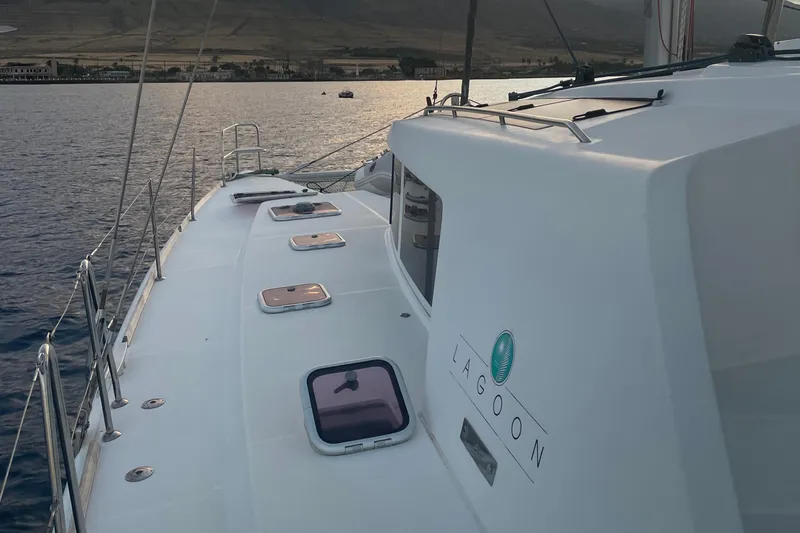 Slide: The Image of 2010 Lagoon 440 catamaran on calm water at sunset, showcasing deck and hatches. - 5