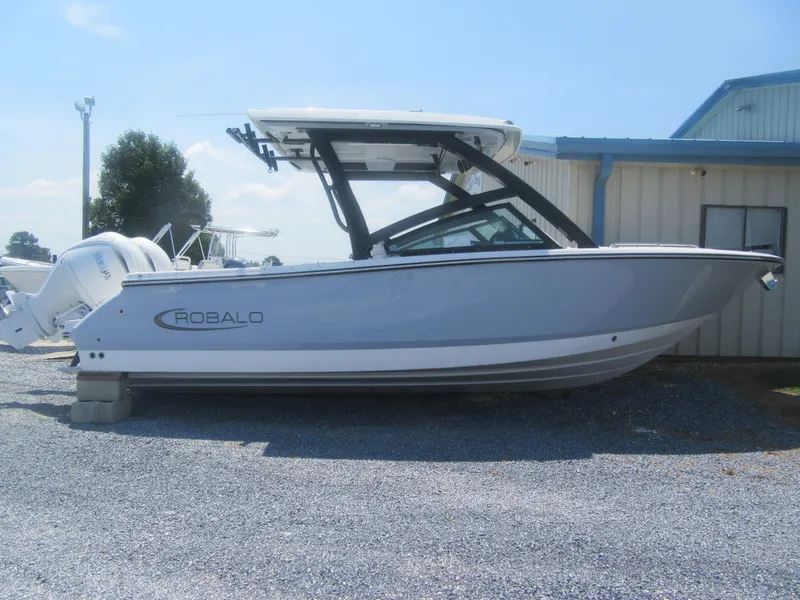 The Image of 2025 Robalo R257 Dual Console boat displayed outdoors on gravel. - 0