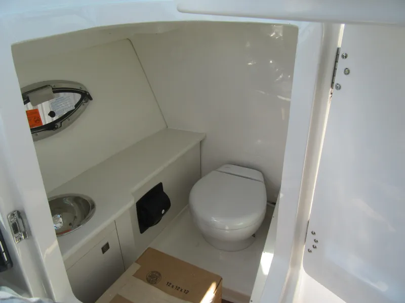 Slide: The Image of 2025 Robalo R257 Dual Console boat interior with compact bathroom and sink. - 16