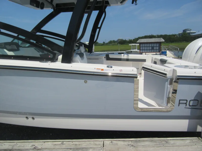 Slide: The Image of 2025 Robalo R257 Dual Console boat docked, showcasing sleek design and open side door. - 3