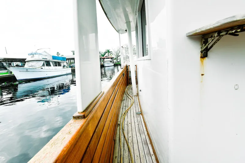 Slide: The Image of 1984 Kadey-Krogen Krogen 42 Trawler side deck with wooden railing and docked boats. - 12