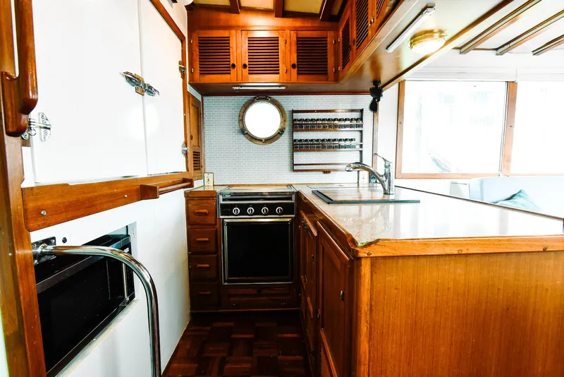 Slide: The Image of 1984 Kadey-Krogen Krogen 42 Trawler kitchen with wooden cabinetry and porthole window. - 22