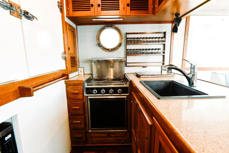 Slide: The Image of 1984 Kadey-Krogen Krogen 42 Trawler kitchen with stove, sink, and wooden cabinetry. - 23