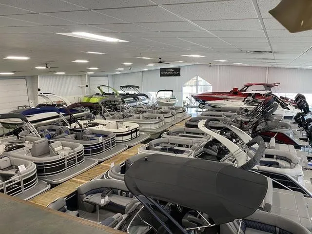 Slide: The Image of Indoor showroom displaying various Bennington pontoon boats, including the 2025 M Swingback 26 MSB model. - 30