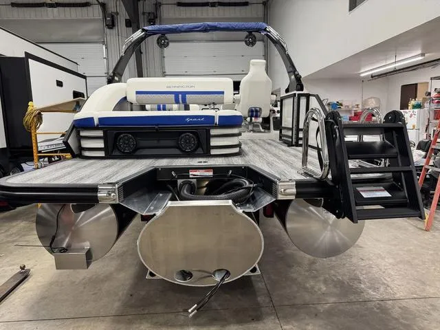 Slide: The Image of 2025 Bennington M Swingback 26 MSB pontoon boat in a garage, showcasing rear deck and seating. - 6