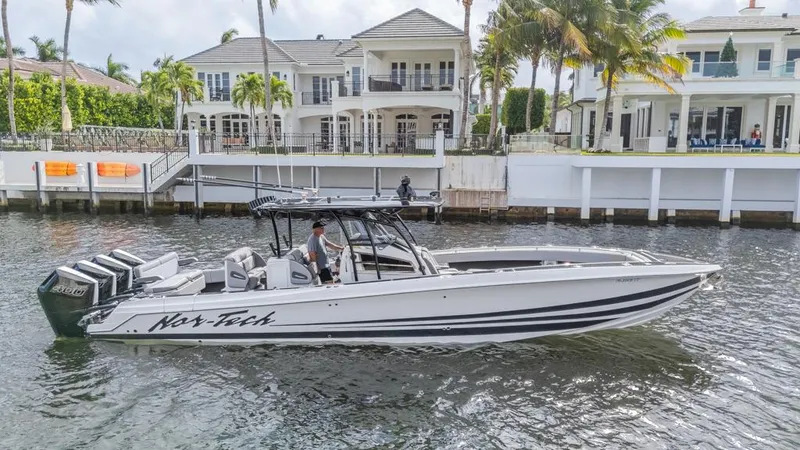 Slide: The Image of 2024 Nor-Tech 392 Super Fish boat cruising near waterfront homes. - 1