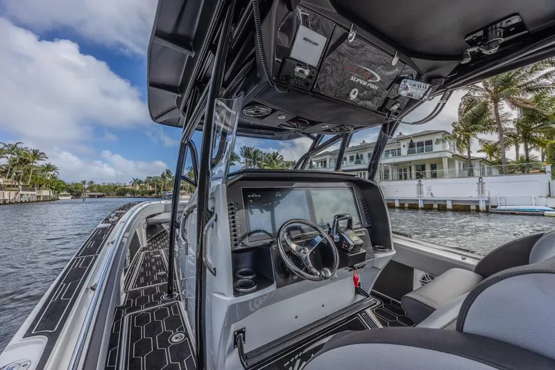 Slide: The Image of 2024 Nor-Tech 392 Super Fish boat interior with advanced navigation system, docked by waterfront homes. - 20