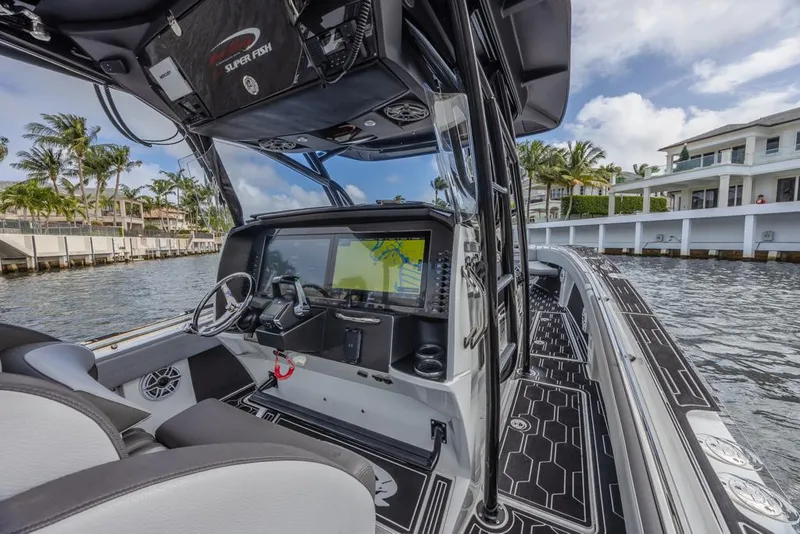 Slide: The Image of 2024 Nor-Tech 392 Super Fish boat interior with advanced navigation system, docked by waterfront homes. - 21