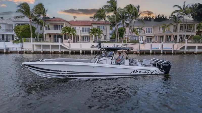 Slide: The Image of 2024 Nor-Tech 392 Super Fish boat cruising near waterfront homes at sunset. - 3