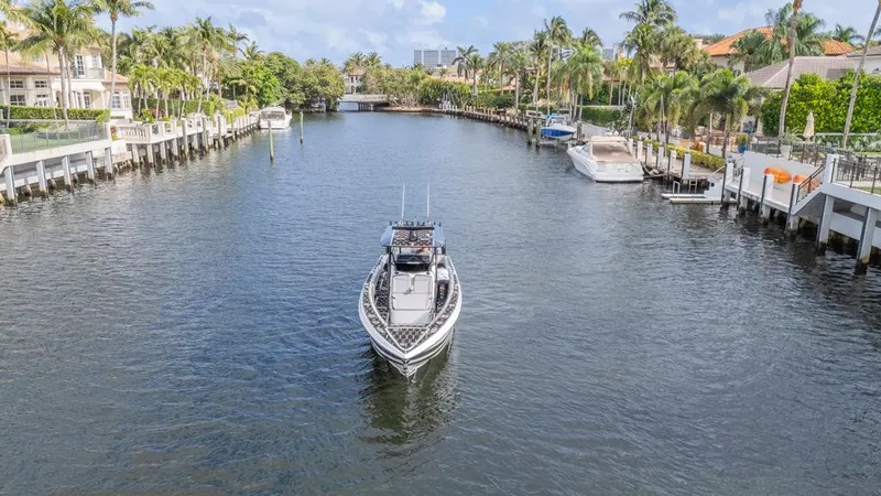 Slide: The Image of 2024 Nor-Tech 392 Super Fish boat cruising in a scenic canal with palm trees. - 8