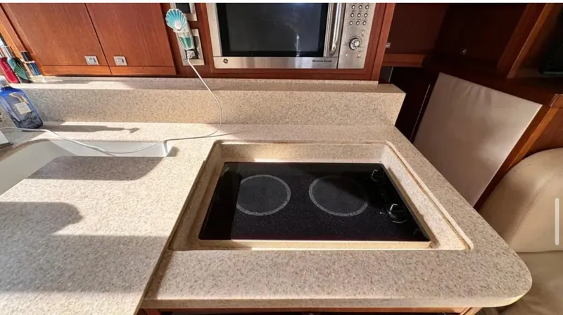 Slide: The Image of 1987 Blackfin Convertible kitchen with stove and microwave, featuring beige countertops. - 28