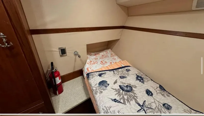 Slide: The Image of 1987 Blackfin Convertible cabin with single bed, nautical-themed bedding, and fire extinguisher. - 39