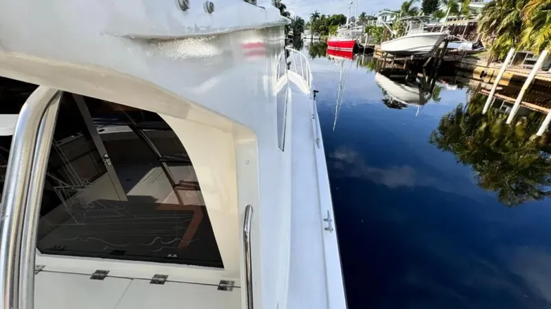 Slide: The Image of 1987 Blackfin Convertible yacht docked on calm water, reflecting nearby boats and palm trees. - 6