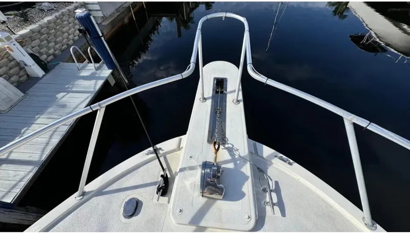 Slide: The Image of Bow of a 1987 Blackfin Convertible boat with anchor and railing, docked by calm water. - 8