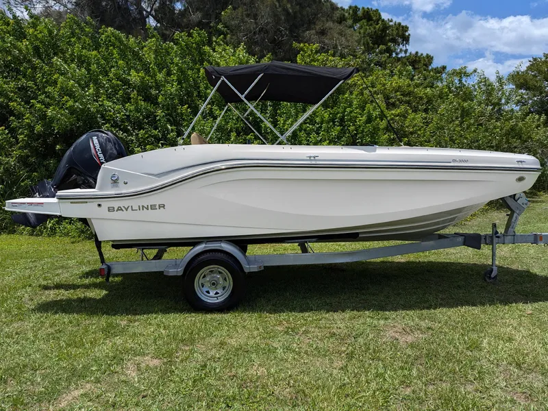 Slide: The Image of 2024 Bayliner DX2000 boat on trailer, parked on grass with trees in background. - 3