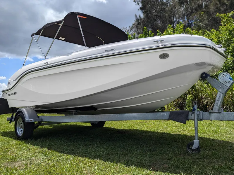 Slide: The Image of 2024 Bayliner DX2000 boat on trailer, parked on grass with a canopy. - 4