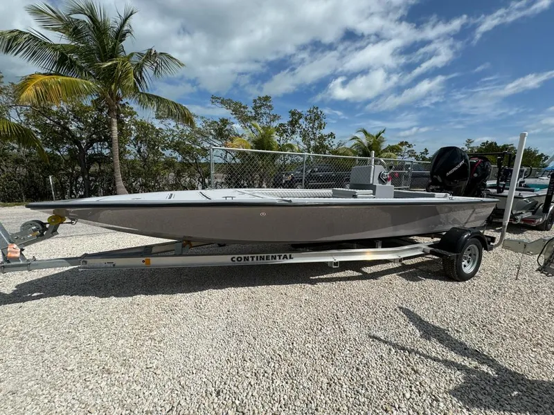 Slide: The Image of Custom Key Hopper 20 boat on trailer, 2023 model, parked on gravel with palm trees. - 4