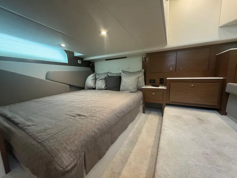 Slide: The Image of Luxurious cabin interior of 2020 Cruisers Yachts 39 Express Coupe with cozy bed and wooden cabinetry. - 39