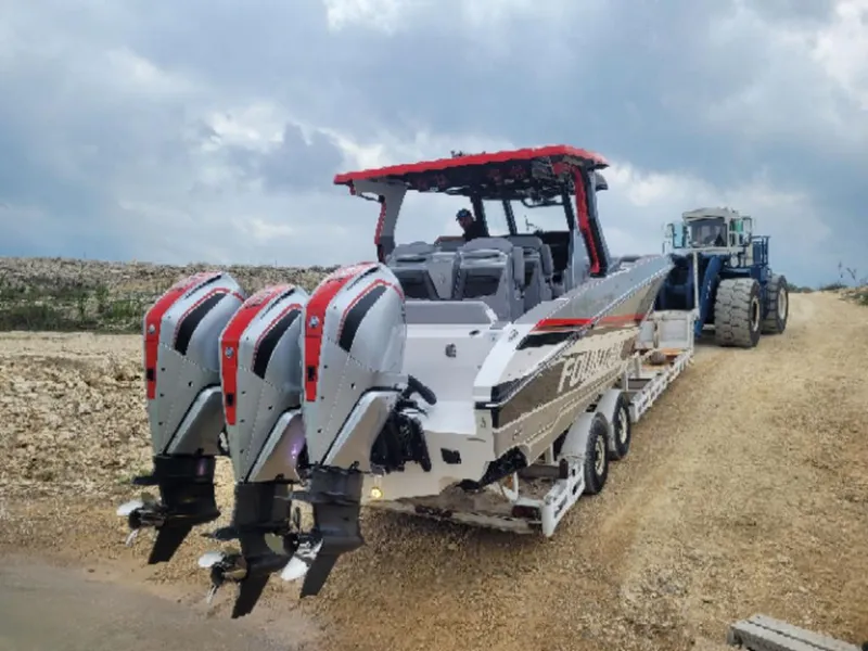 Slide: The Image of 2024 Fountain 38 SCX boat with triple engines on a trailer, cloudy sky background. - 19