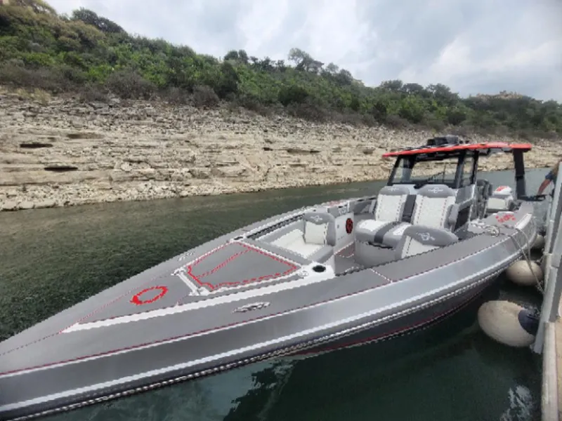 Slide: The Image of 2024 Fountain 38 SCX boat docked by rocky shoreline. - 23