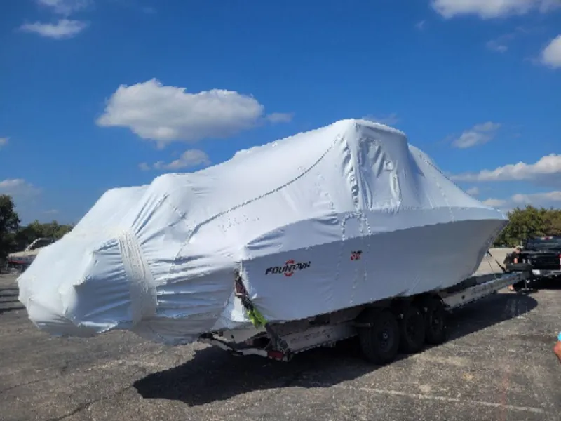 Slide: The Image of 2024 Fountain 38 SCX boat covered in protective wrap on a trailer under a blue sky. - 4