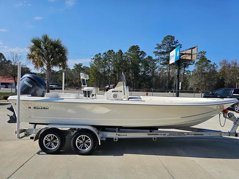 Slide: The Image of 2025 Bulls Bay 2200 XS boat on trailer, parked outdoors under clear blue sky. - 6