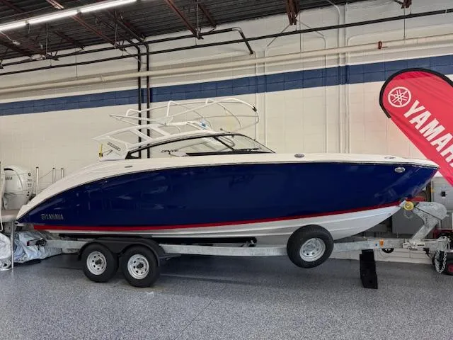 The Image of 2025 Yamaha Boats 252SD in showroom, blue hull, on trailer, indoor display. - 0