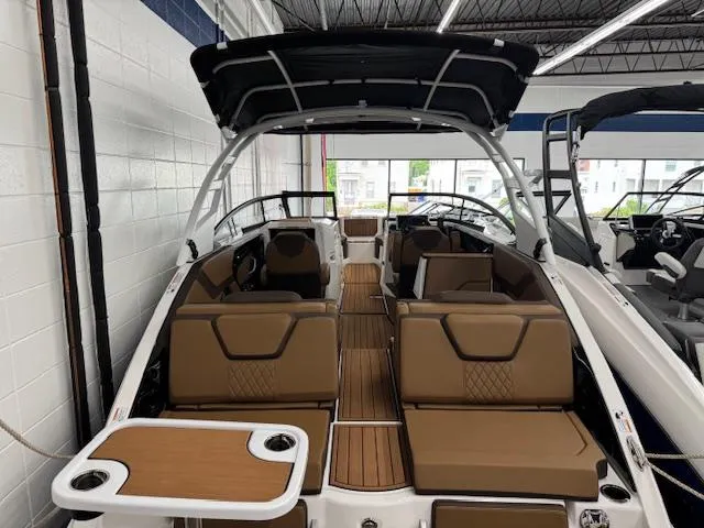 Slide: The Image of 2025 Yamaha Boats 252SD interior with brown seating and table, showcased in a showroom. - 19