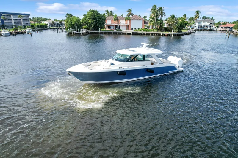 Slide: The Image of 2022 Tiara Yachts 48 LS cruising on a scenic waterway with palm trees. - 3