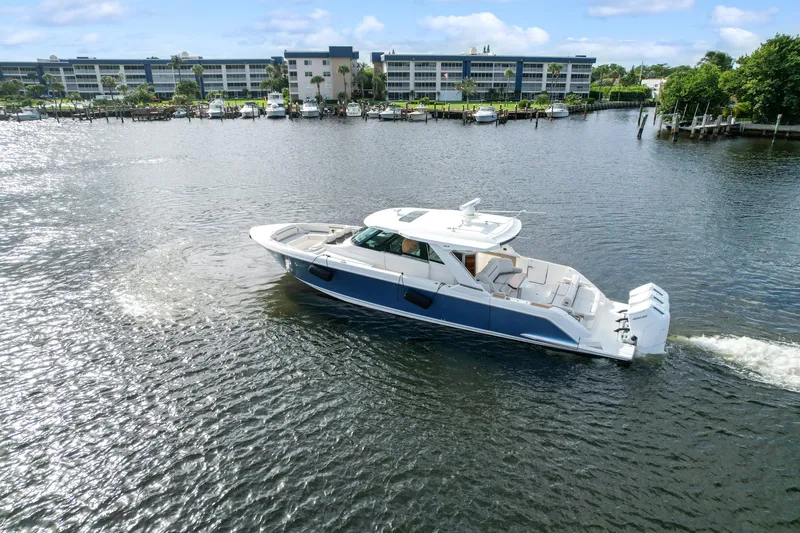 Slide: The Image of 2022 Tiara Yachts 48 LS cruising on a scenic waterfront with buildings in the background. - 4