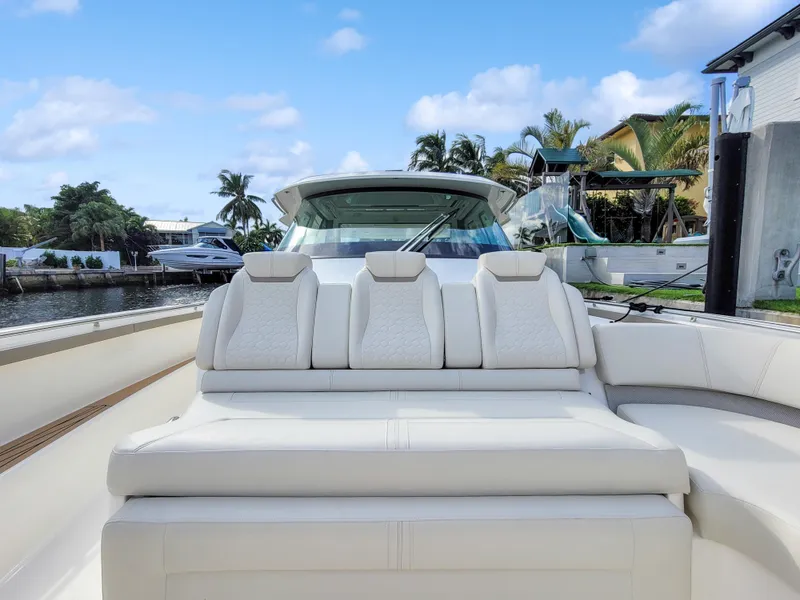 Slide: The Image of 2022 Tiara Yachts 48 LS luxury boat with plush seating, docked by palm trees. - 8