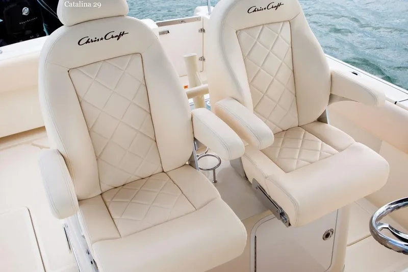 Slide: The Image of 2015 Chris-Craft Catalina 29 boat interior with beige seating and helm, docked by water. - 4