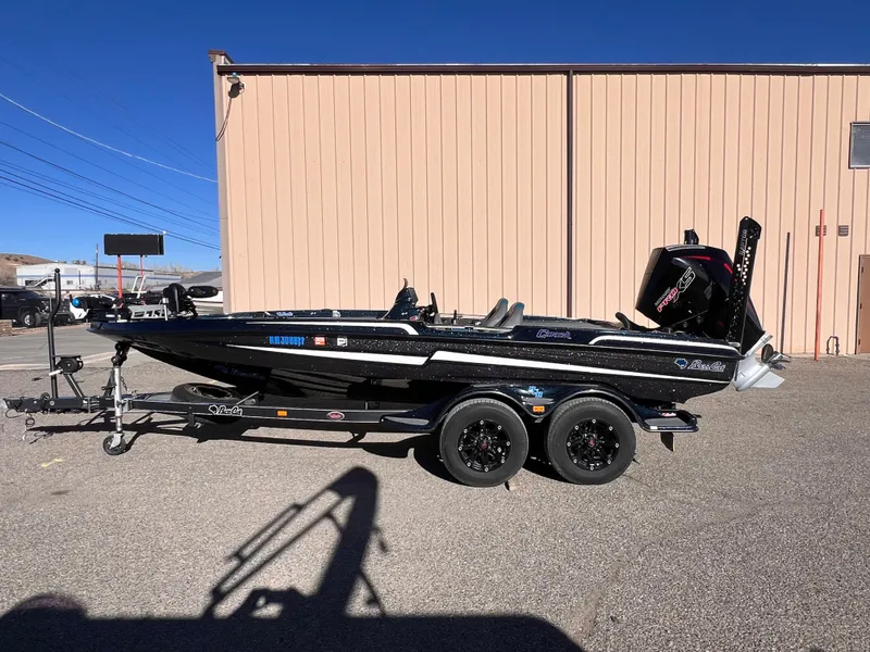 Slide: The Image of 2021 Bass Cat Caracal boat on trailer, parked outdoors under clear blue sky. - 0