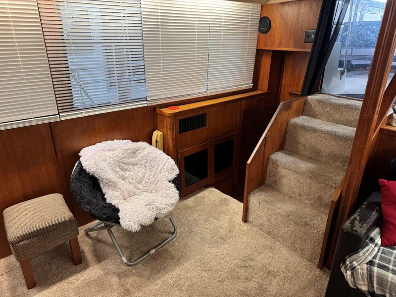 Slide: The Image of 1988 Chris-Craft 426 Catalina interior with cozy seating, carpeted stairs, and wooden paneling. - 22
