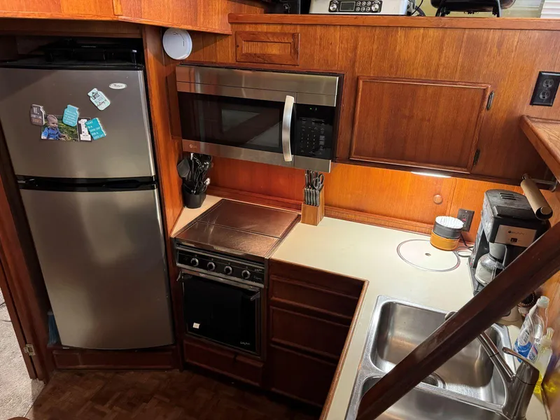 Slide: The Image of 1988 Chris-Craft 426 Catalina kitchen with stainless appliances and wooden cabinetry. - 26