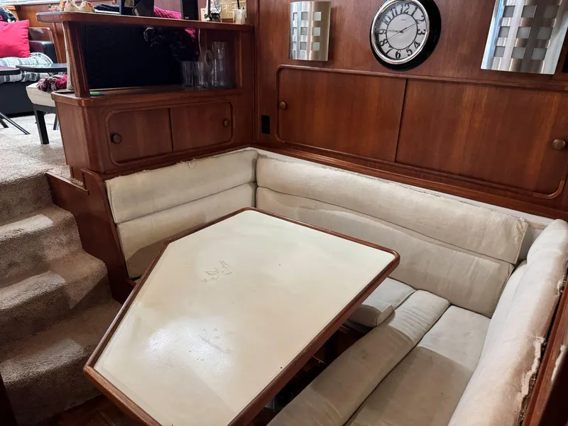 Slide: The Image of 1988 Chris-Craft 426 Catalina interior with wooden paneling, clock, and cushioned seating area. - 29